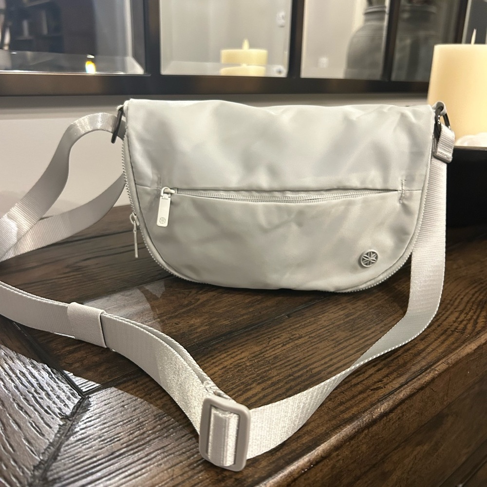 Gaiam crossbody bag in light grey color.